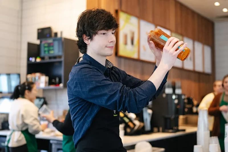 A barista shaking a drink behind the counter.